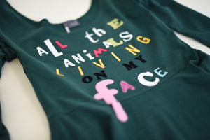 Green dress with multi-colored lettering in various fonts, which spell out the phrase, 